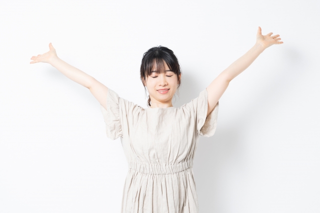 両手を大きく広げて深呼吸する女性