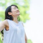 屋外で腕を広げ深く息を吸う女性