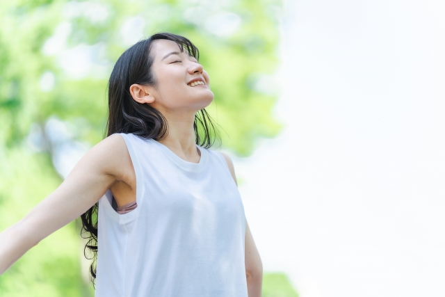 屋外で腕を広げ深く息を吸う女性
