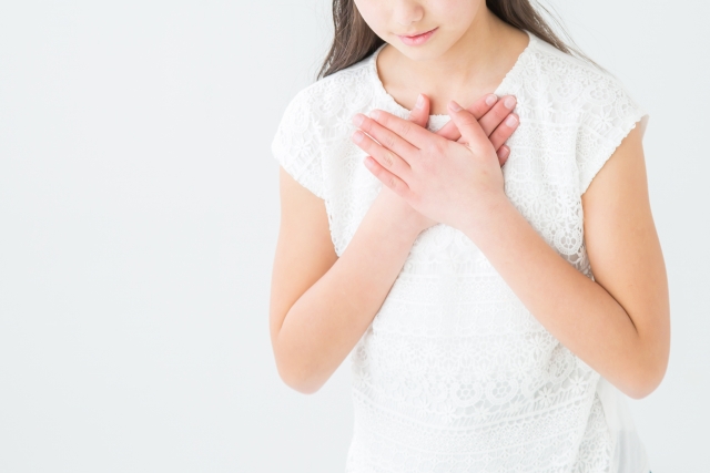 両手を胸に当てる女性