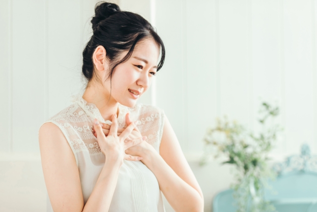 胸元を押さえて顔をしかめる女性