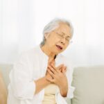 ソファで胸に手を当てる高齢女性