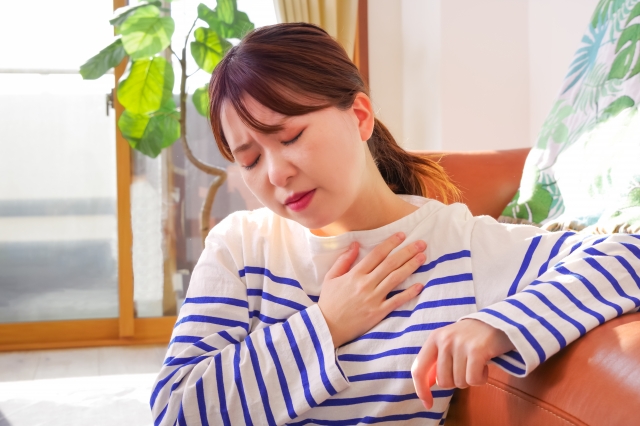 胸に手を当て息苦しそうな女性