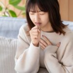 ソファで胸を押さえてうつむく女性