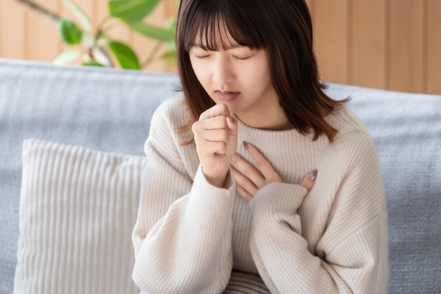 ソファで胸を押さえてうつむく女性